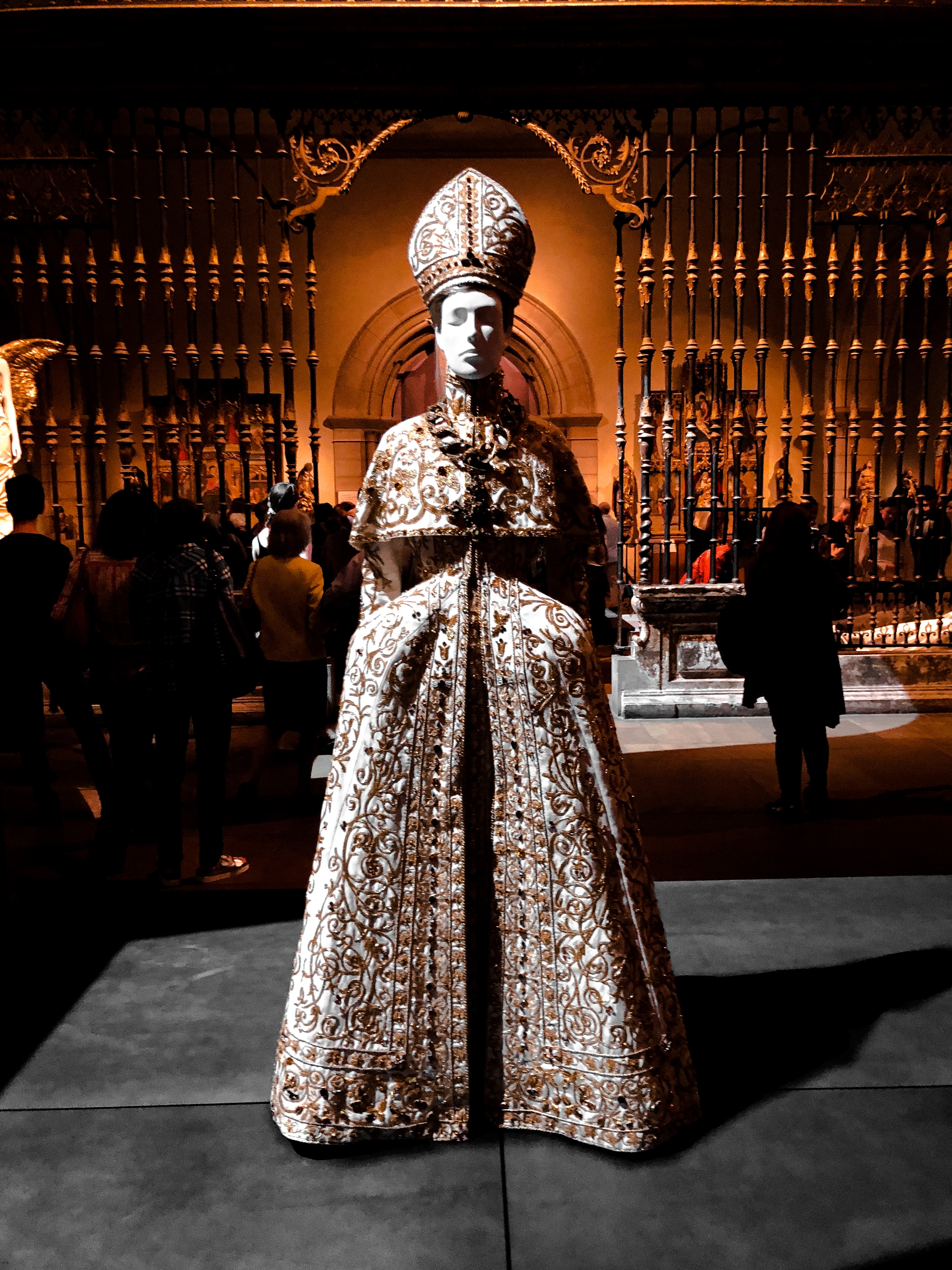 white mannequin wearing embroidered pope-like robe and hat